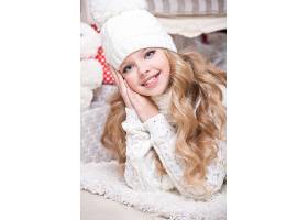 圣诞节趴在毛毯上的针织帽金发小女孩
