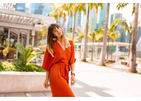 一位身着橙色连衣裙的时髦女子在现代大城市_919846001
