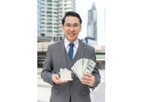 亚洲商人肖像手持现金美元钞票和商业区_11872303