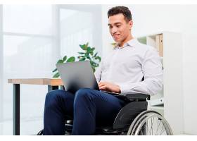 快乐的残疾年轻商人坐在轮椅上在办公室里_4400017