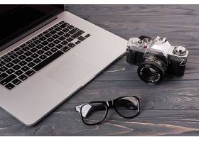 桌上有相机和眼镜的笔记本电脑_3688230