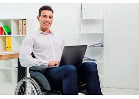 一位面带微笑的年轻人坐在轮椅上手持笔记_4400020