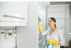 一位戴着橡胶手套的年轻女子在打扫冰箱_1281450