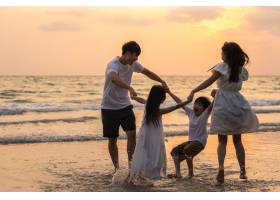 亚洲年轻幸福的一家人晚上在海滩上享受假期_7685878