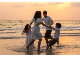 亚洲年轻幸福的一家人晚上在海滩上享受假期_7685877
