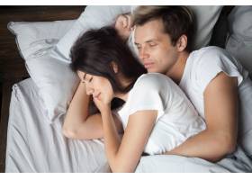 年轻夫妇在一起睡觉拥抱躺在舒适的床上_3938900