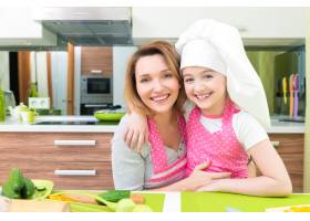 厨房里穿着粉色围裙的幸福微笑的母女的肖像_11177205