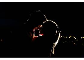 一对可爱的年轻夫妇在夜里站在屋顶上的剪影_2612656