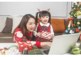 快乐的妈妈和小女儿在家里装饰圣诞树和礼物_11548029