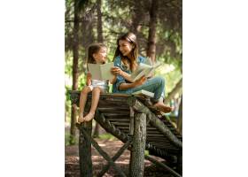 年轻的母女俩在木桥上的树林里看书幸福的_10108157