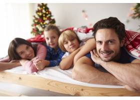 圣诞节期间躺在床上的一家人_11728029