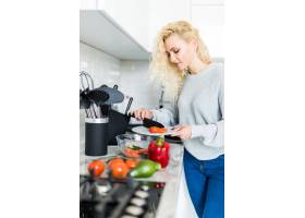 年轻快乐的女人在漂亮的厨房里切西红柿做沙_8472850