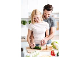 幸福的年轻夫妇在厨房里一起做饭的肖像_8078420