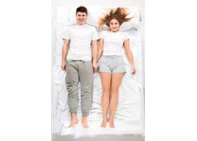 这对年轻可爱的夫妇躺在一张白色的床上爱_9480152