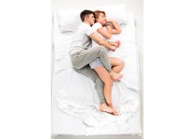 这对年轻可爱的夫妇躺在一张白色的床上爱_9480166