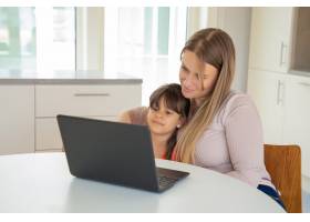 宁静的女孩和她的妈妈使用笔记本电脑坐在_9988592
