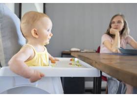 可爱的红发新生儿坐在白色塑料婴儿厨房座椅_9649973
