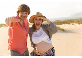 幸福的丈夫和怀孕的妻子在海滩上玩耍_6101354