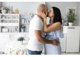 中等镜头的丈夫和怀孕的妻子接吻_5171787
