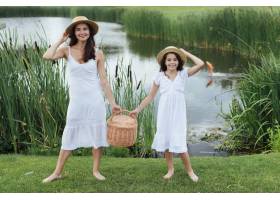 母女俩在湖边提着野餐篮_4962074