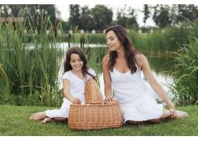 母女俩在湖边提着野餐篮_4962102