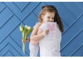 快乐的女儿在蓝色的背景下拿着鲜花和贺卡拥_4048386