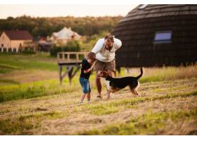 一个男人和他的儿子和一条狗在操场上玩耍_2915111