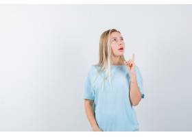 蓝色T恤杉的白肤金发的女孩指向与食指向_13665294