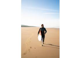 有截肢的腿的活躍沖浪者走在與沖浪板的海灘_13996020