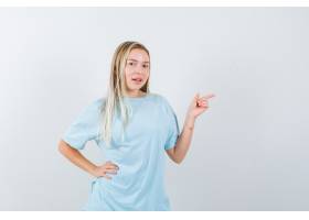 指向与食指的白肤金发的女孩握在蓝色T恤_13664308