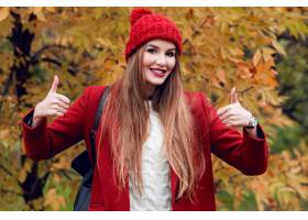 摆在秋天公园的红色帽子和夹克的愉快的成功_9419156