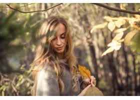 有长的头发的美丽的女孩在秋天森林秋天季