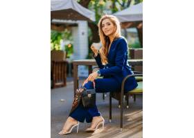 有吸引力的时髦的女人穿着蓝色典雅的衣服坐_13868832