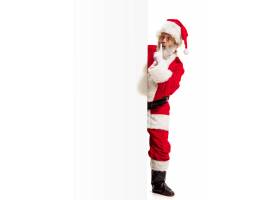 愉快的惊奇的圣诞老人指向在空白的广告墙壁
