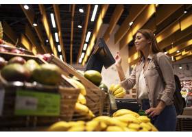 超市的妇女使用自助数字标度来测量水果的重_11450349