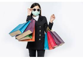 年轻女子穿着黑暗面具和眼镜和袋子去购物