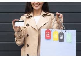 阻止信用卡和购物袋的妇女正面图与销售标记