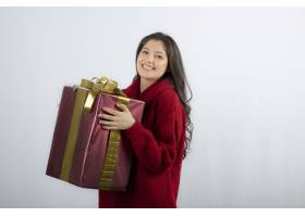 微笑着拿着圣诞礼品盒的美丽年轻女子免费