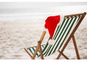 圣诞老人帽子放在空沙滩椅上免费拍照
