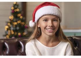 小女孩戴着圣诞老人的无帽照片微笑着