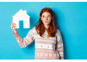 房地产概念体贴的红发女孩展示纸房子模型