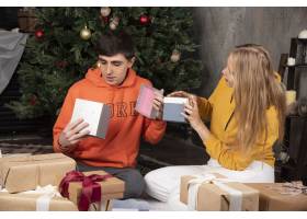 这对年轻夫妇在家里用礼物庆祝圣诞节免费