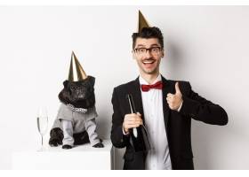 小黑狗戴着派对帽站在快乐男人庆祝节日的